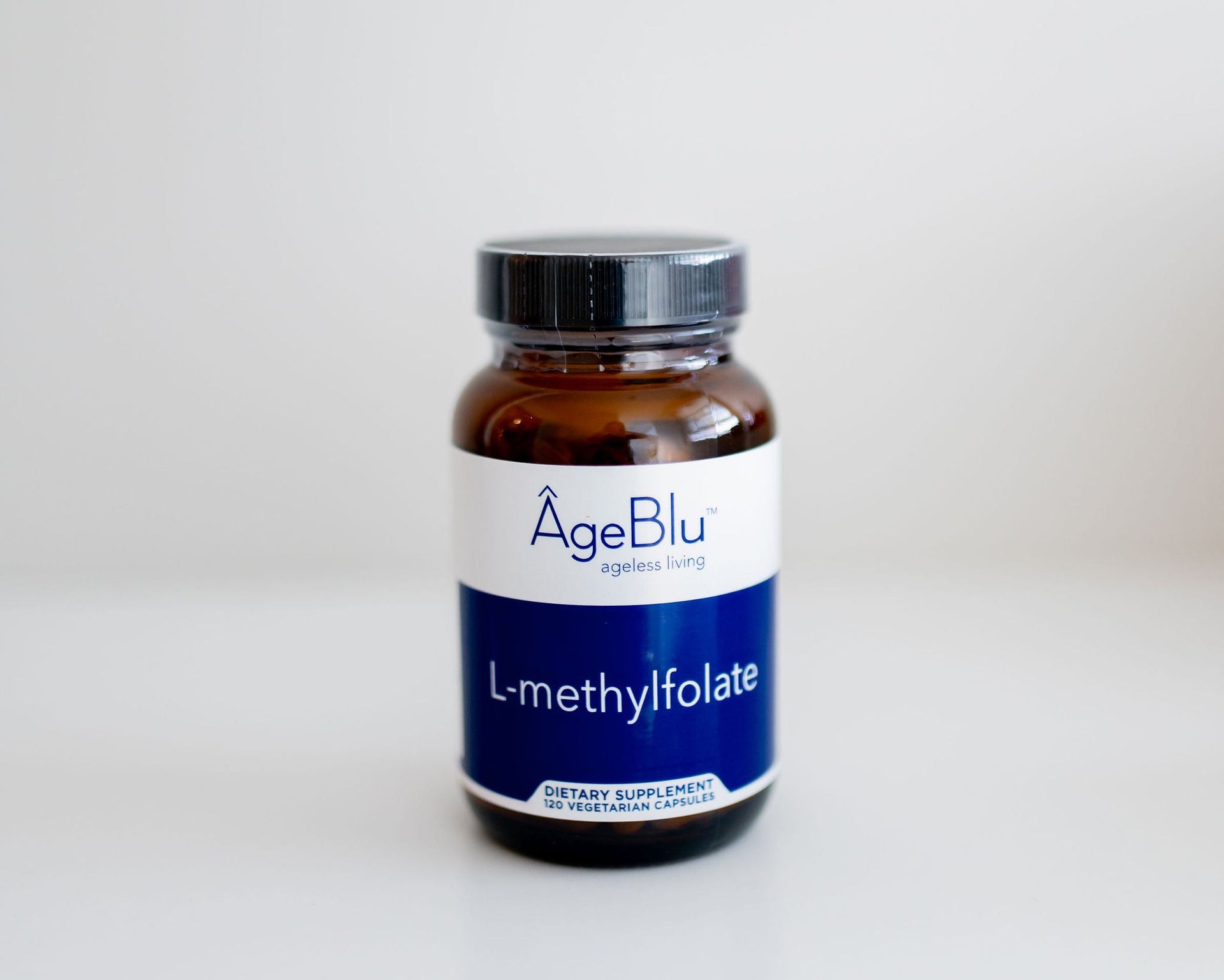 An amber glass bottle of AgeBlu L-methylfolate dietary supplement with a white and blue label, set against a plain white background.